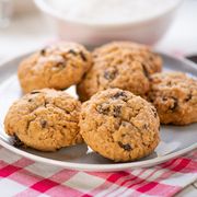 golden brown oatmeal cookie with raisins on a rustic red checked tablecloth