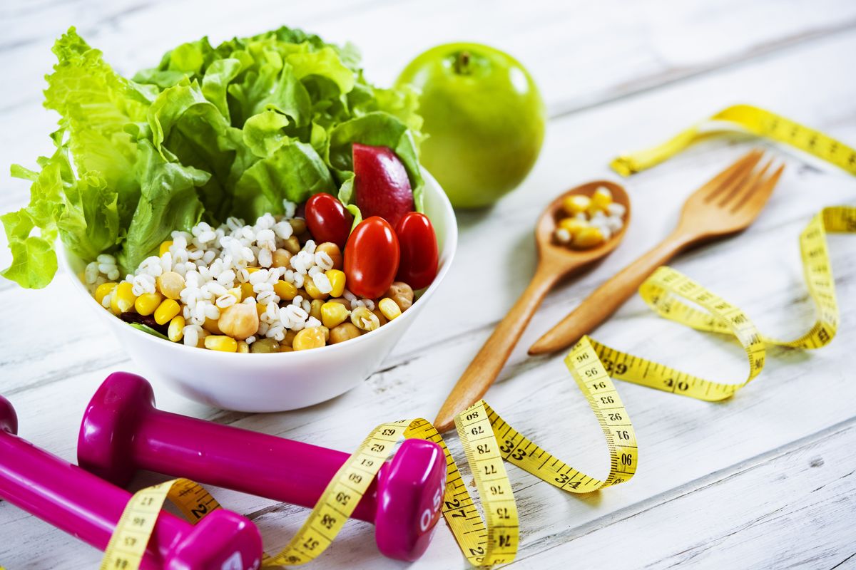 healthy eating and exercising backgrounds fresh healthy salad and dumbbells and tape measure