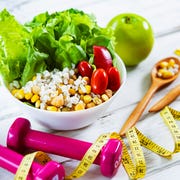 Healthy eating and exercising backgrounds: Fresh healthy salad, dumbbells and tape measure healthy eating and exercising with fresh healthy salad and dumbbells and tape measure