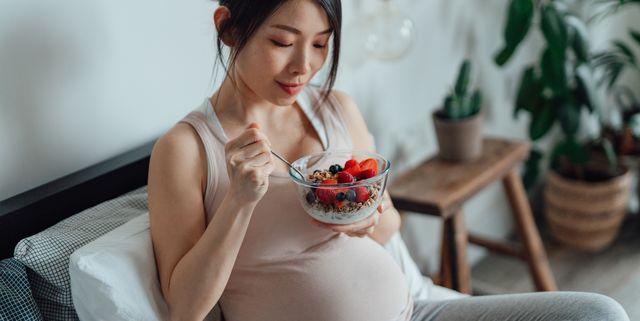 mujer embarazada con bol de fruta desayunando
