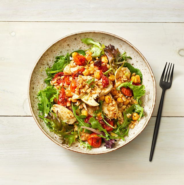 chickpeas and roasted tomatoes on a bed a leafy greens