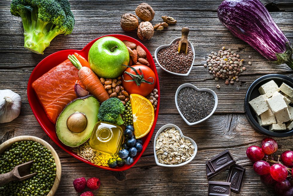 sobre una tabla de madera se sitúan alimentos que te ayudar a llevar una alimentación saludable con frutas, verduras, cereales