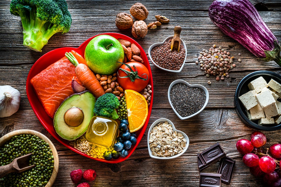 sobre una tabla de madera se sitúan alimentos que te ayudar a llevar una alimentación saludable con frutas, verduras, cereales