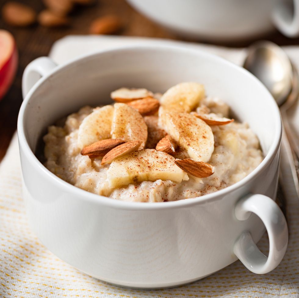oatmeal porridge with banana, cinnamon and almonds in white bowl healthy breakfast food