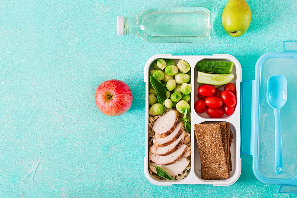 Healthy green meal prep containers with chicken fillet, rice, brussels sprouts and vegetables overhead shot with copy space. Dinner in lunch box. Top view. Flat lay
