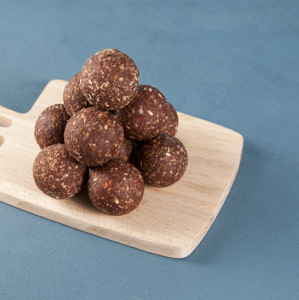 healthy homemade sweets on a wooden serving board energy balls laid out in the form of a pyramid made from dates, apricots, almonds, pine nuts and prunes, with honey