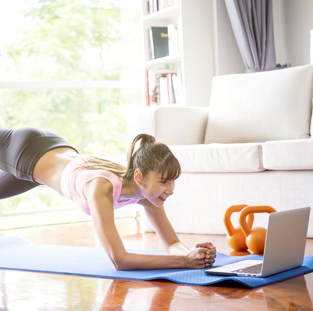 healthy lifestyle and work life balance concepts young woman doing yoga excercise with online app on computer laptopn in her living room at home