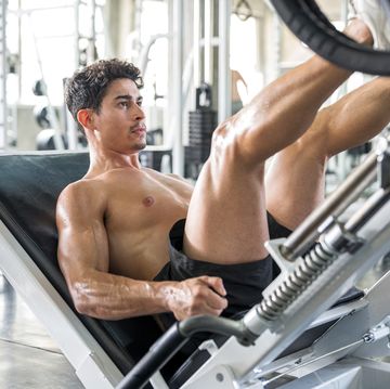 healthy lifestyle, exercising and people concepts muscular man doing leg presses on leg press machine in the gym