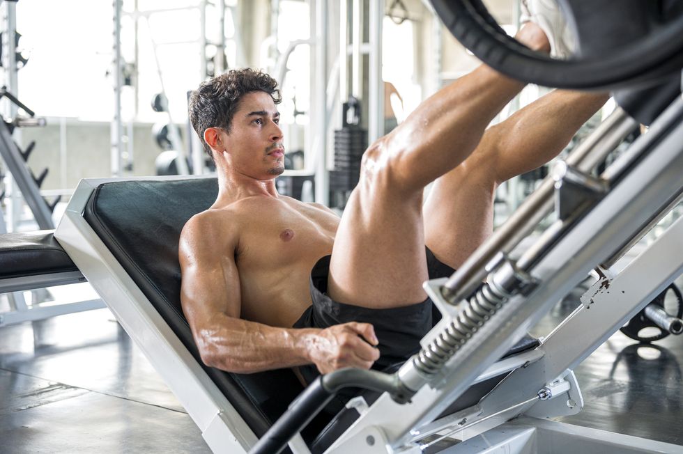 ragazzo che fa un macchinario per gambe in palestra senza maglia