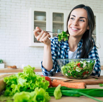 healthy lifestyle good life organic food vegetables close up portrait of happy cute beautiful young woman while she try tasty vegan salad in the kitchen at home