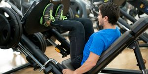 healthy man exercising at the gym on a leg press machine