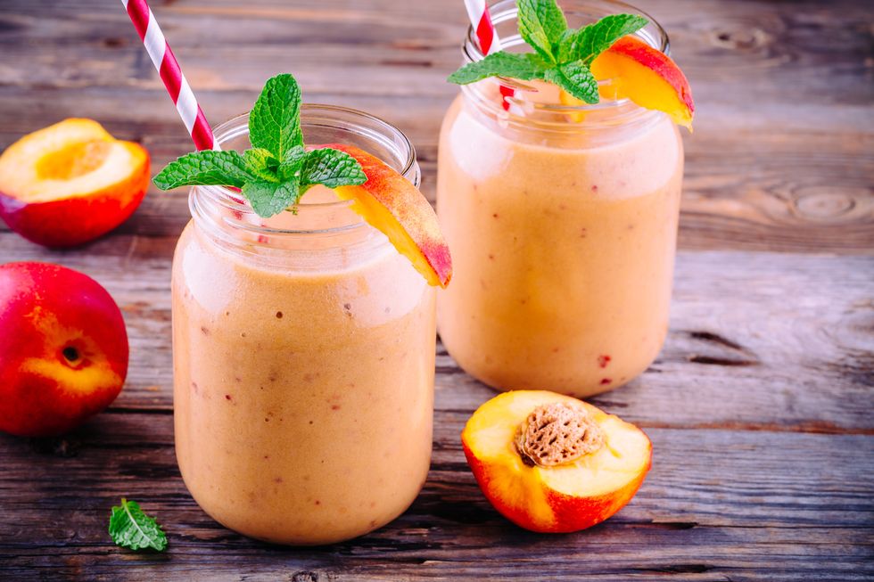 healthy nectarine smoothies in a mason jar with mint on wooden background