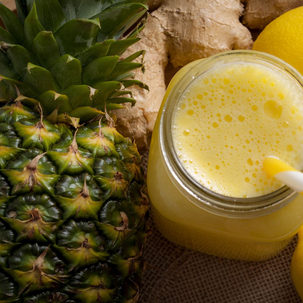 juicing raw fruits and vegetables and juice extractor recipes concept with pineapple, lemon and ginger, the ingredients for a detox smoothie that helps with inflammation and digestion