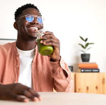 african american black man drinking healthy green juice with bamboo straw looking at camera copy space wellness and healthy lifestyle concept