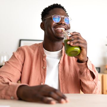 african american black man drinking healthy green juice with bamboo straw looking at camera copy space wellness and healthy lifestyle concept