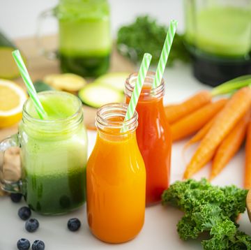 high angle view of fresh fruits and vegetables juices in bottles and mason jars shot on kitchen table