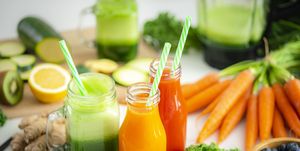 high angle view of fresh fruits and vegetables juices in bottles and mason jars shot on kitchen table
