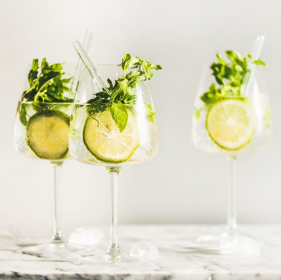 hugo sparkling wine cocktail with fresh mint and lime in glasses with eco friendly straws over white marble counter, selective focus. cold refreshing summer alcoholic drink hugo sparkling wine cocktail with fresh mint and lime in glasses with eco friendly straws over white marble counter, selective focus. cold refreshing summer alcoholic drink
