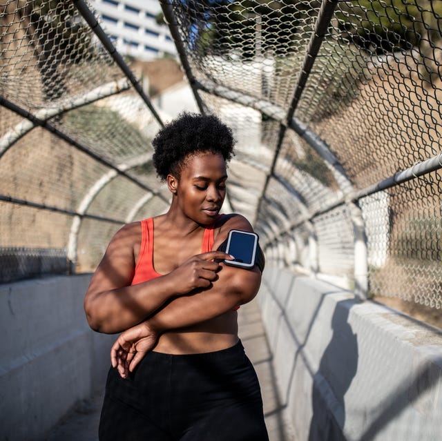 healthy woman using phone on armband before exercising