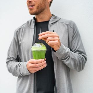 healthy young man drinking green juice smoothie cup as weight loss detox meal replacement diet spinach protein shake for morning breakfast