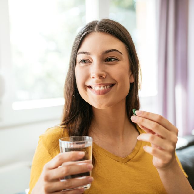 healthy young woman taking herbal supplements