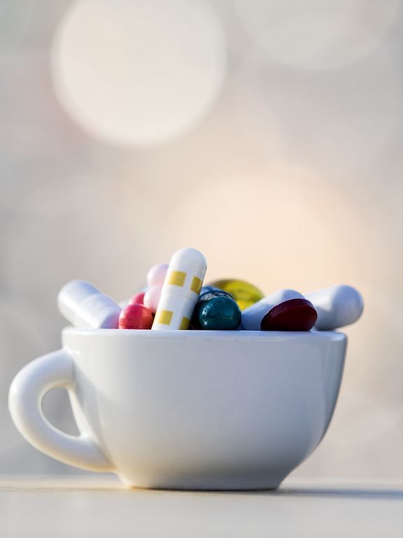 Heap of medicines in tablets and pills of colors, inside in a cup of coffee