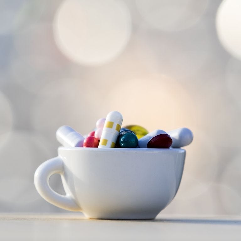 Heap of medicines in tablets and pills of colors, inside in a cup of coffee