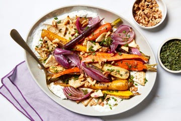 roasted vegetables with chicken and nuts on a serving platter