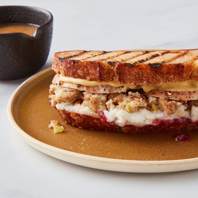 a grilled sandwich with turkey stuffing and cranberry sauce on a plate beside a cup of coffee a grilled sandwich with turkey stuffing and cranberry sauce on a plate beside a cup of coffee