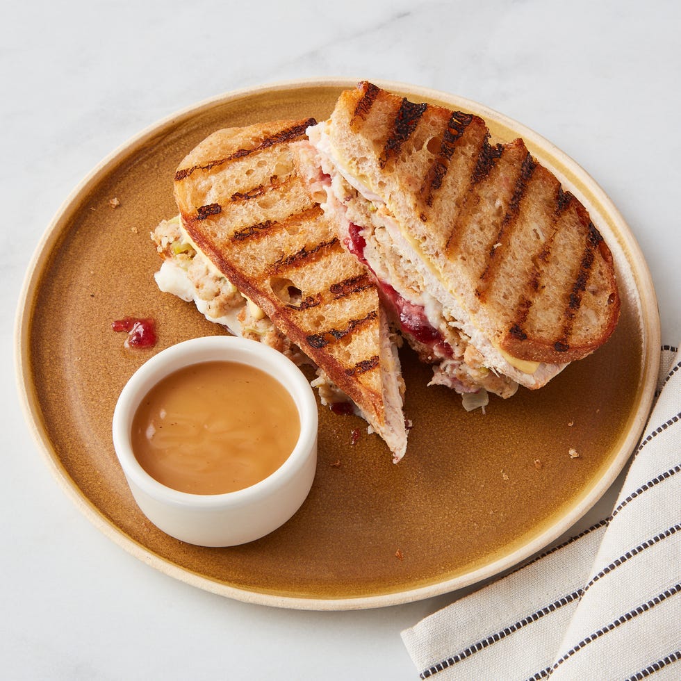 grilled sandwich served on a plate with a small bowl of sauce grilled sandwich served on a plate with a small bowl of sauce