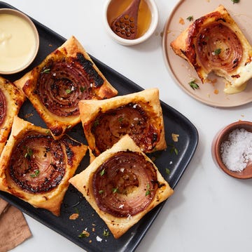 savory pastries topped with caramelized onions on a black tray savory pastries topped with caramelized onions on a black tray