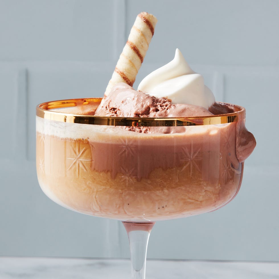 a dessert glass filled with a layered chocolate drink and ice cream topped with whipped cream and a chocolate wafer stick a dessert glass filled with a layered chocolate drink and ice cream topped with whipped cream and a chocolate wafer stick