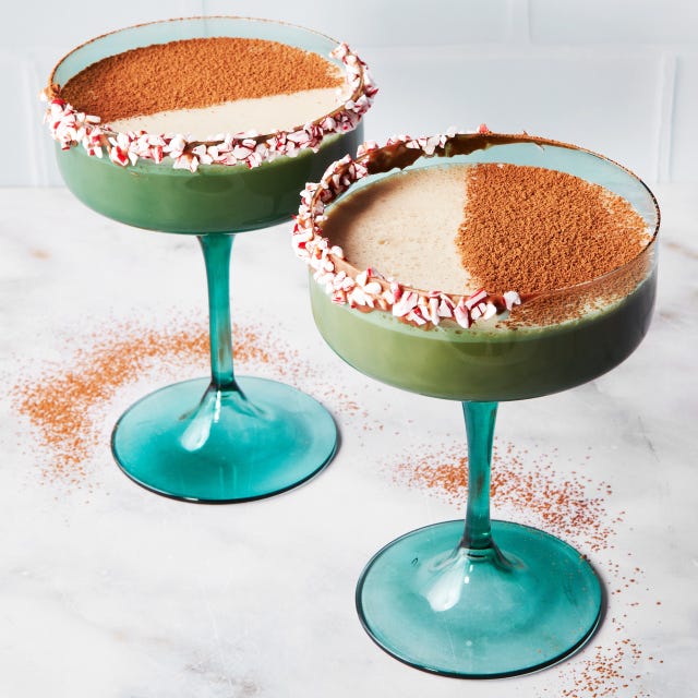 two cocktails in green glasses topped with crushed peppermint and cocoa powder