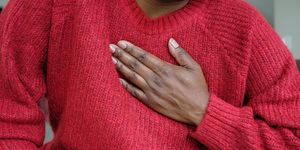 close up of unrecognizable black woman holding her chest in pain