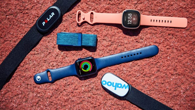 a number of heart rate monitor straps and watches on the ground of a running track
