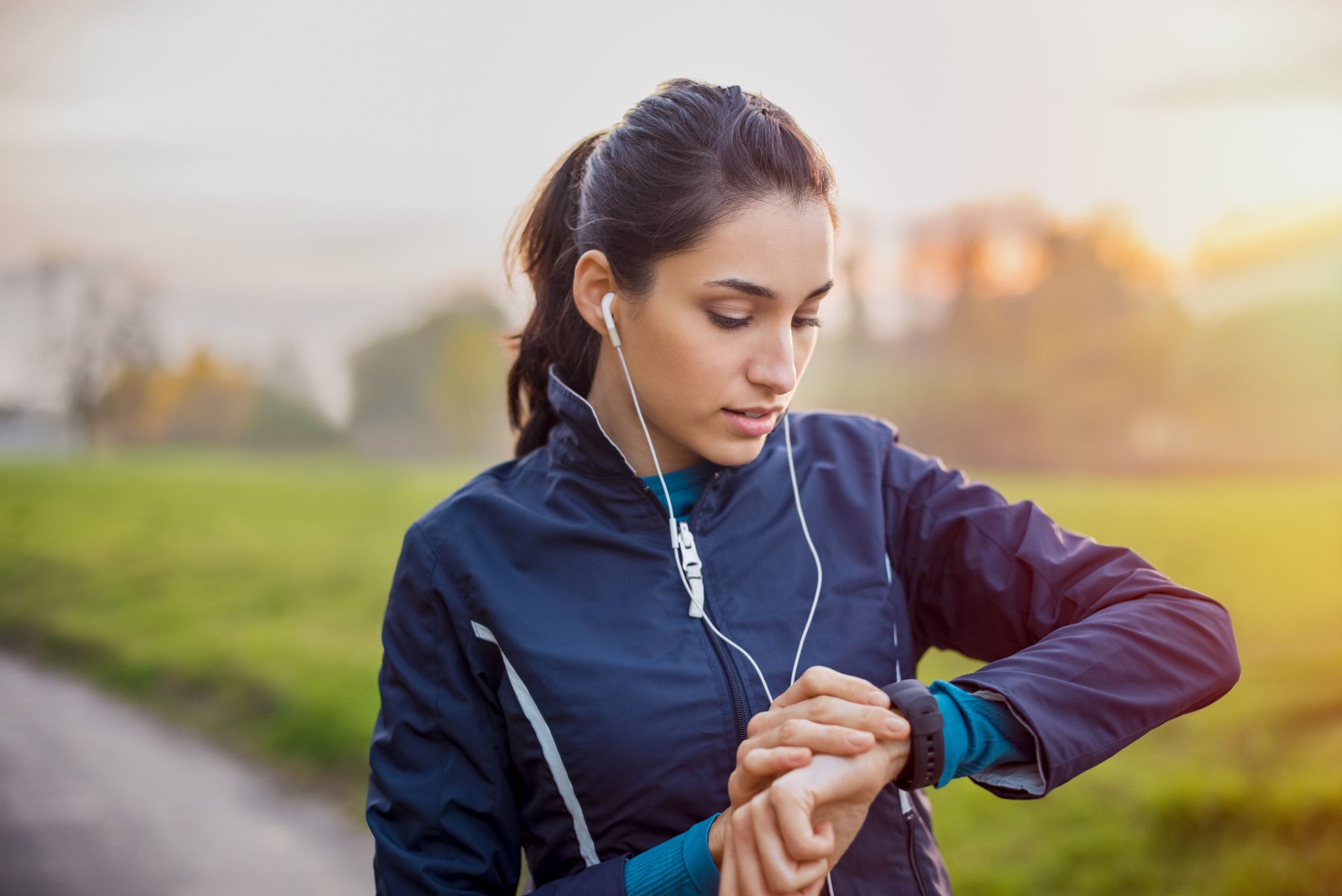 young athlete listening to music during workout at park and adjusting smart watch