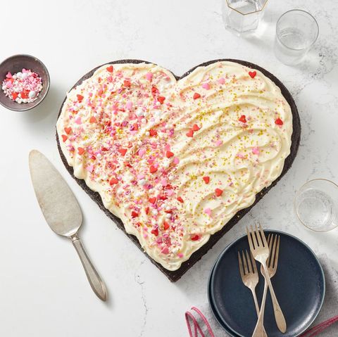 heart shaped cake with white frosting and red and pink sprinkles