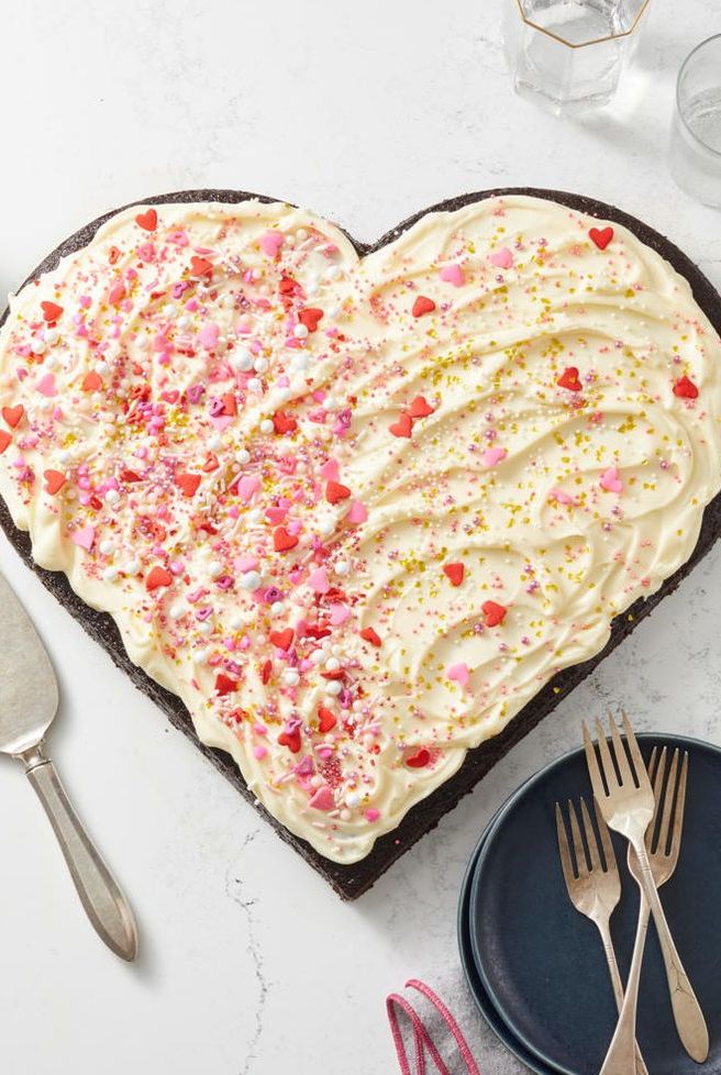heart shaped cake with white frosting and heart sprinkles