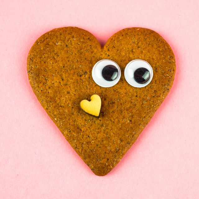 a heart shaped ginger cookie with eyes and a wooden heart self love concept