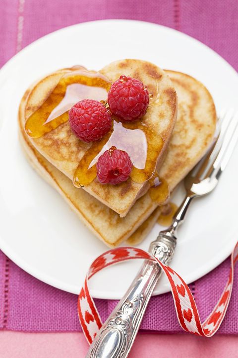 heart shaped pancakes with syrup and raspberries on top