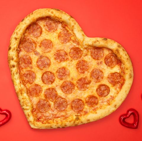heart shaped pizza pepperoni for valentines day on red paper background