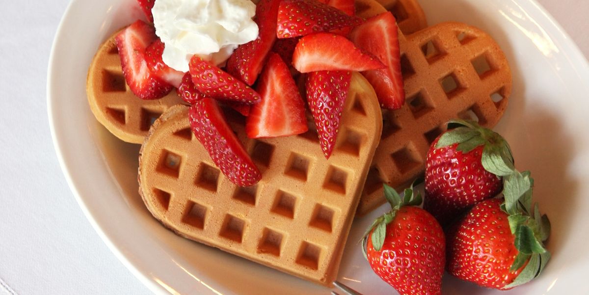 heart shaped waffles topped with fresh strawberries and whipped cream perfect for mothers day or valentines day