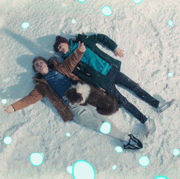 charlie and nick in heartstopper, two teenage boys wear winter clothes as they lie on the floor in snow