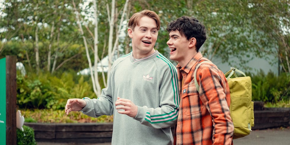 two people engaged in conversation outdoors with greenery in the background