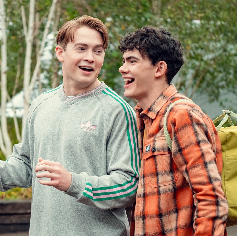 two people engaged in conversation outdoors with greenery in the background two people engaged in conversation outdoors with greenery in the background