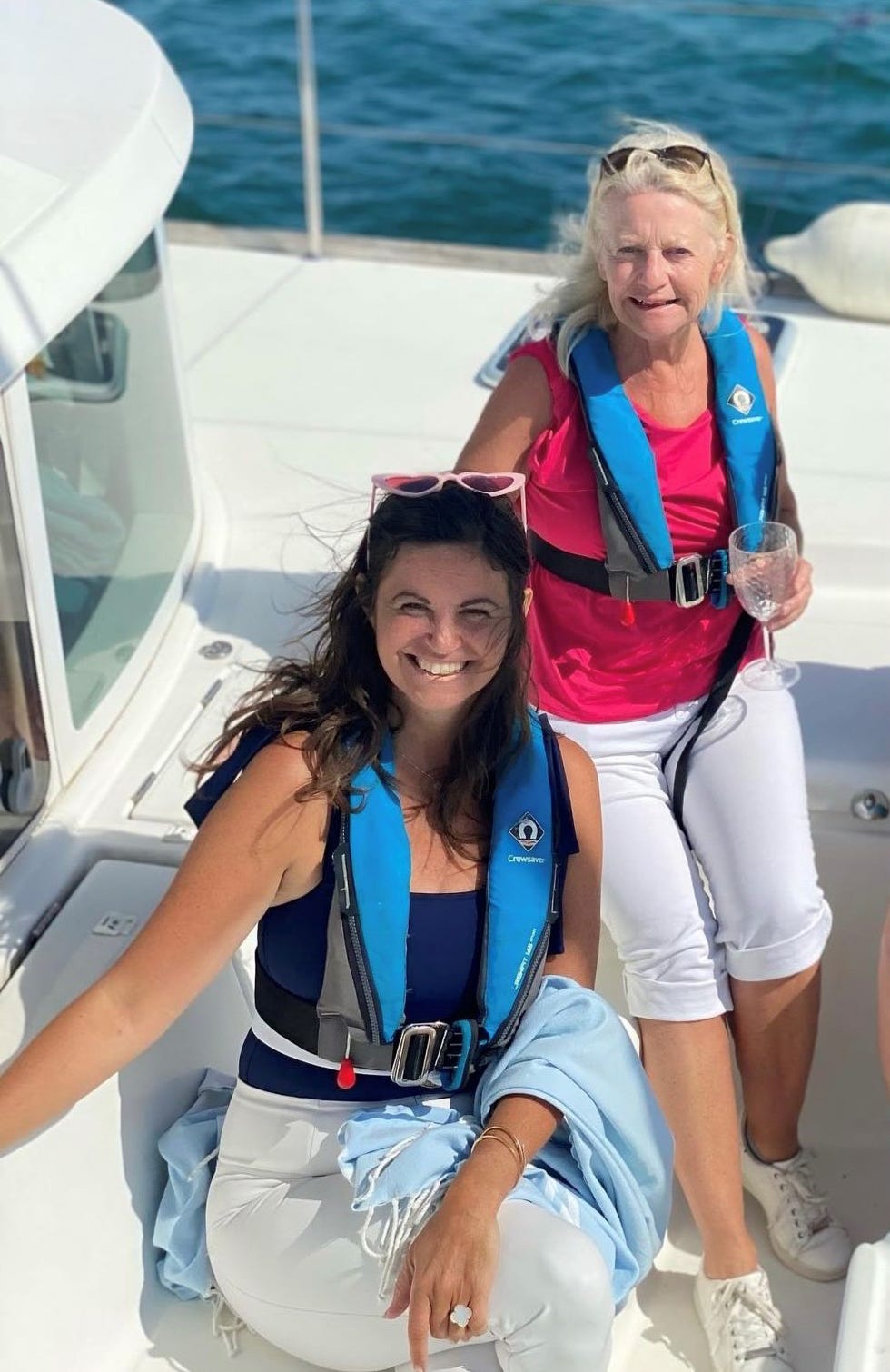 two women wearing life jackets on a boat enjoying a sunny day at sea