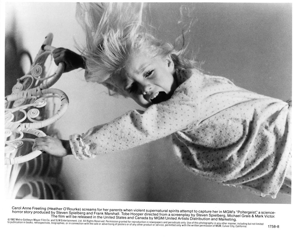 heather o'rourke screams as she is suspended in air and hangs on to a bed frame, she wears polka dot pajamas