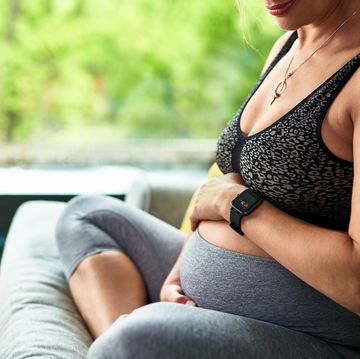 heavily pregnant woman wearing fitness tracker holding bump