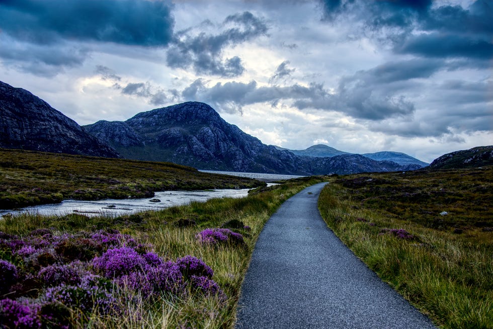 a path winds its way through green fields and mountains on the isle of lewis
