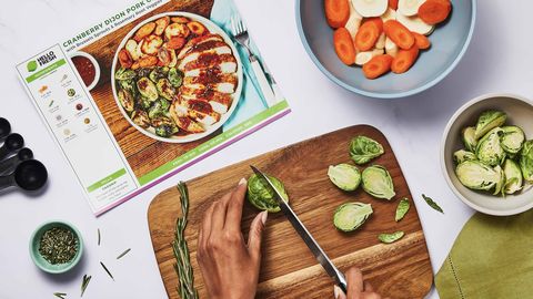 cheapest meal delivery service kit, hello fresh, image of brussels sprouts being sliced on a wooden cutting board with recipe card